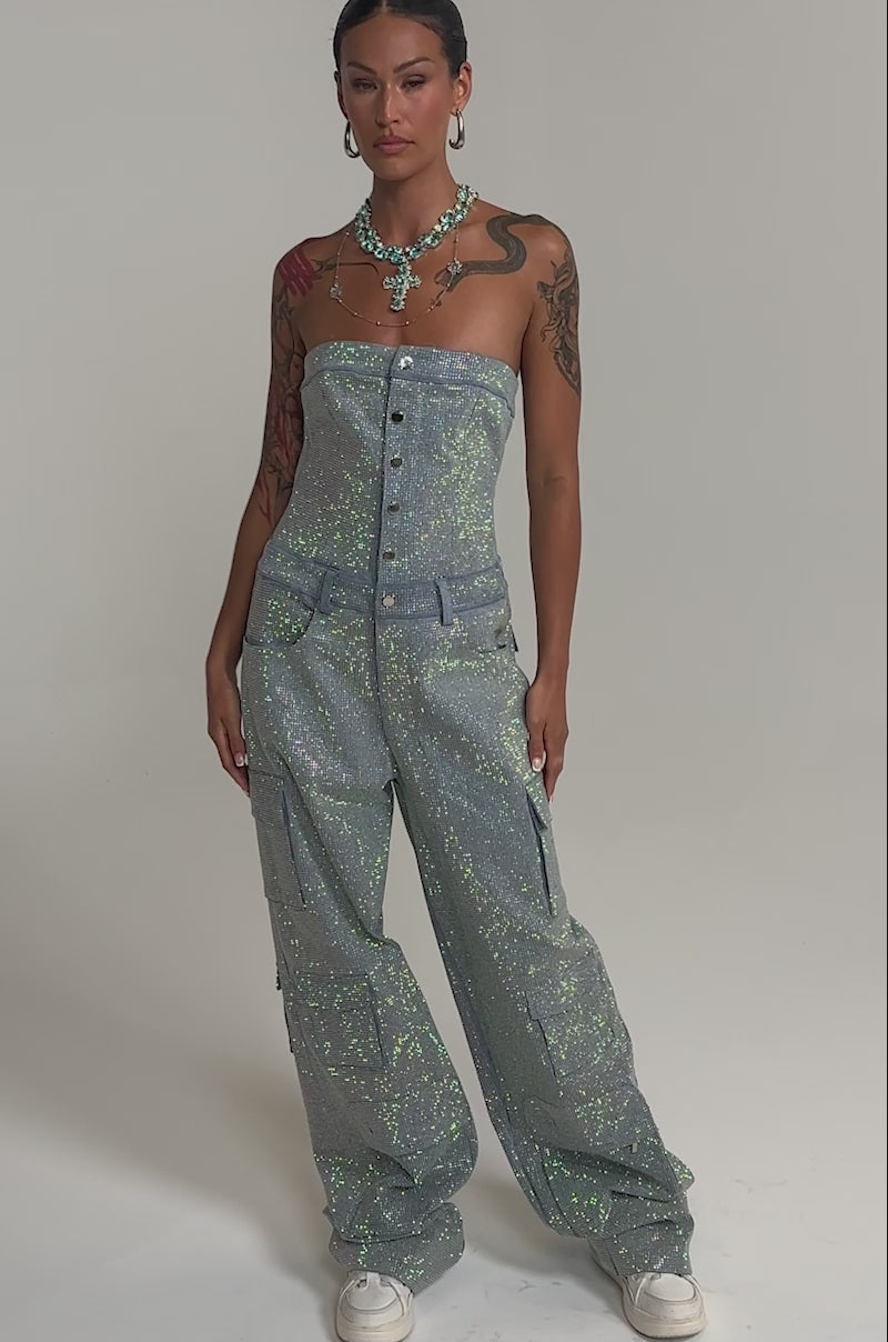 Video of woman modeling the TOO FLY RHINESTONE DENIM JUMPSUIT with wide-leg pants, white sneakers, and layered necklaces.