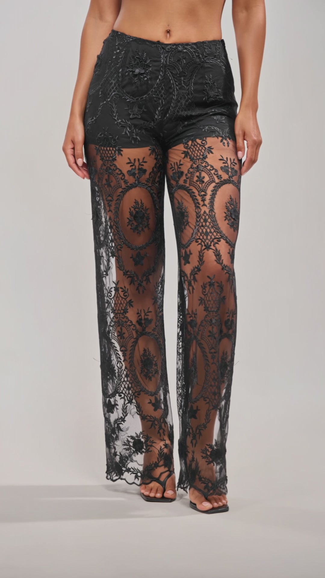 A video of a person wearing the SUPER LUXE WIDE-LEG PANT—high-waisted, black sheer lace with intricate embroidery—paired with black high-heeled sandals.