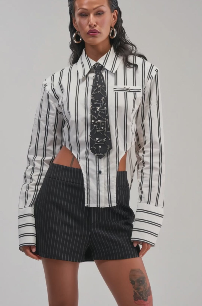 Video of a woman modeling the ON TOP POPLIN BUTTON DOWN—a black-and-white striped poplin top featuring cut-out sides.
