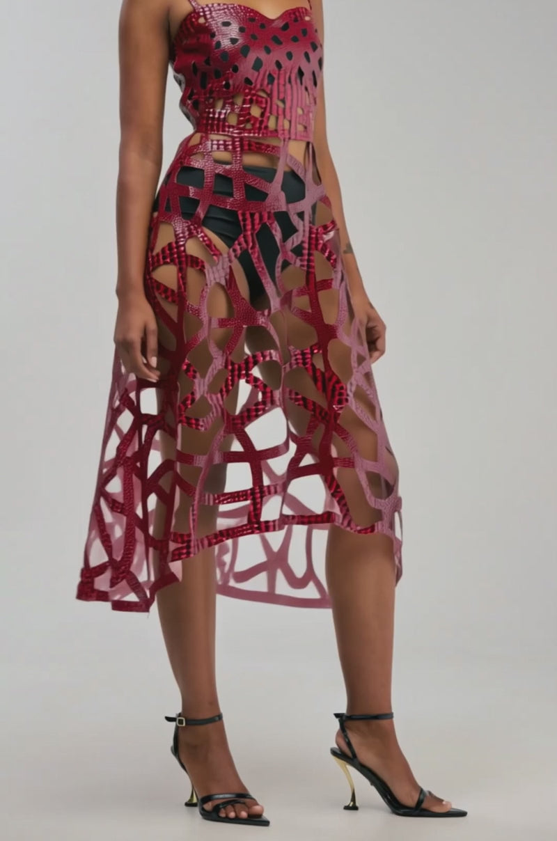 Video of a woman modeling the LOCKED IN LOVE PU CAGE DRESS IN BURGUNDY CROC—a sleeveless faux leather midi dress with red geometric cutouts.background.