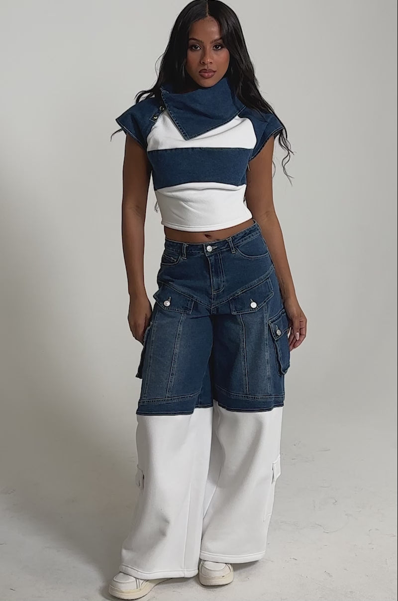 Video of woman modeling the THIS IS EVERYTHING YOU SEE DENIM BLOUSE—a cropped, fitted top with wide blue and white stripes and a mock-style oversized collar—paired with blue jeans.