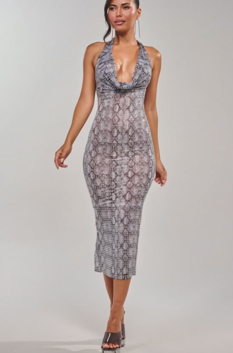 A video of a woman in the LENNON PRINTED MESH RHINESTONE MIDI DRESS IN PYTHON, a sleeveless, form-fitting snake print halter dress with a deep neckline, paired with heeled sandals.