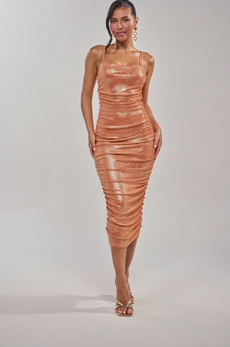 A video of a woman in the KILL THE LIGHTS Strapless Rhinestone Midi Dress in Peach Bellini. 