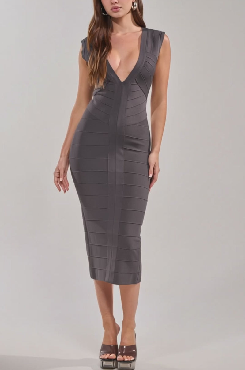 Video of woman modeling the SOFT GLAM BANDAGE MIDI DRESS, featuring a grey hue, deep V neckline, and below-the-knee hem. 