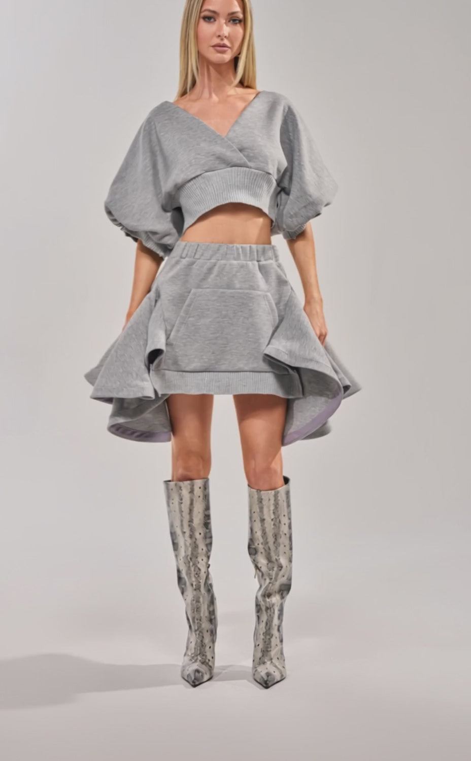 Video of woman modeling the NO WORK ALL PLAY SCUBA SWEATSHIRT—a grey, cropped streetwear top with wide sleeves—paired effortlessly with a matching high-waisted skirt and large front pocket for a cool, laid-back look.