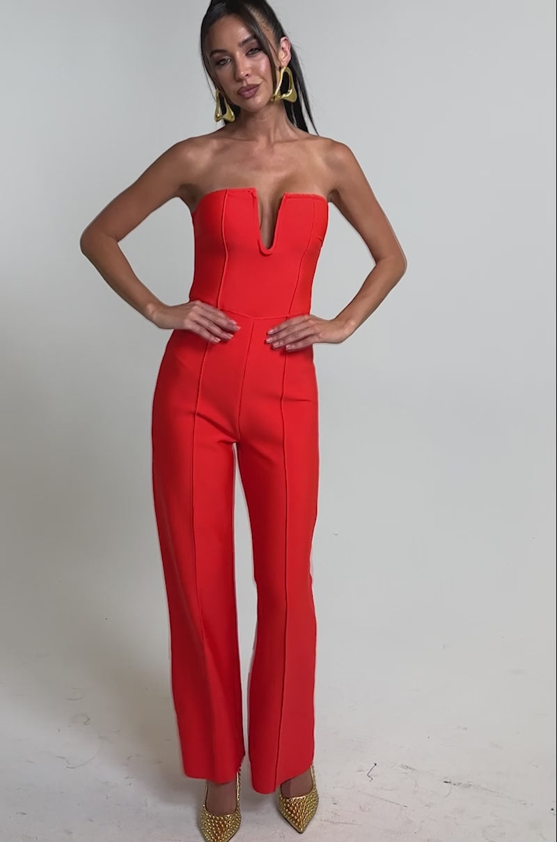 A video of a woman in the BOSS LADY JUMPSUIT IN RED, a strapless wide-leg jumpsuit with a deep V neckline.
