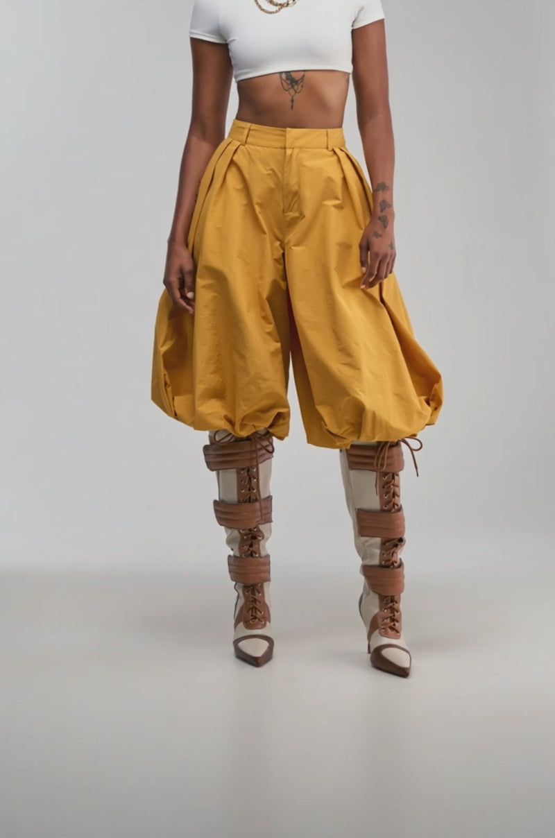 Video of a woman modeling the GLOW GAUCHO PANT IN MUSTARD with a balloon leg silhouette.