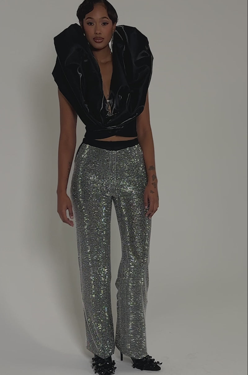 Video of woman modeling the DROP IT LOW BLOUSE, a satin top with a dramatic oversized collar, paired with sparkly high-waisted fitted cropped pants, standing against a neutral background.