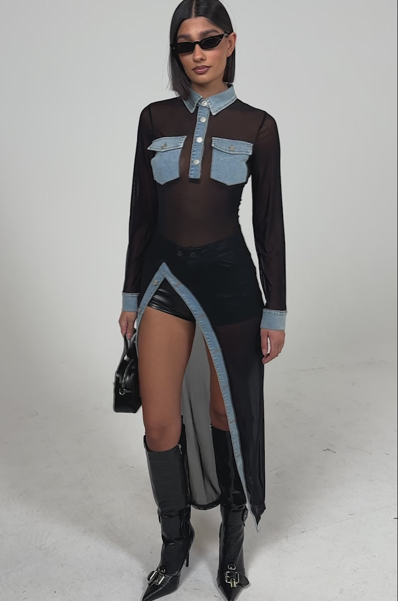 A video of a woman wearing sunglasses, black shorts, knee-high black boots, and holding a small black handbag poses against a plain light background in the SABRINA LONG MESH BUTTON DOWN TOP.