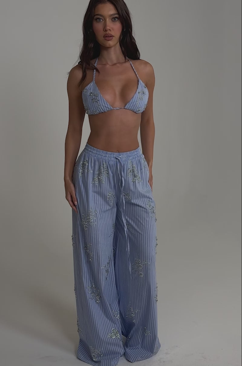 A video of a woman wearing the SWEET DREAMS RHINESTONE POPLIN BRALETTE and wide-leg floral pants.