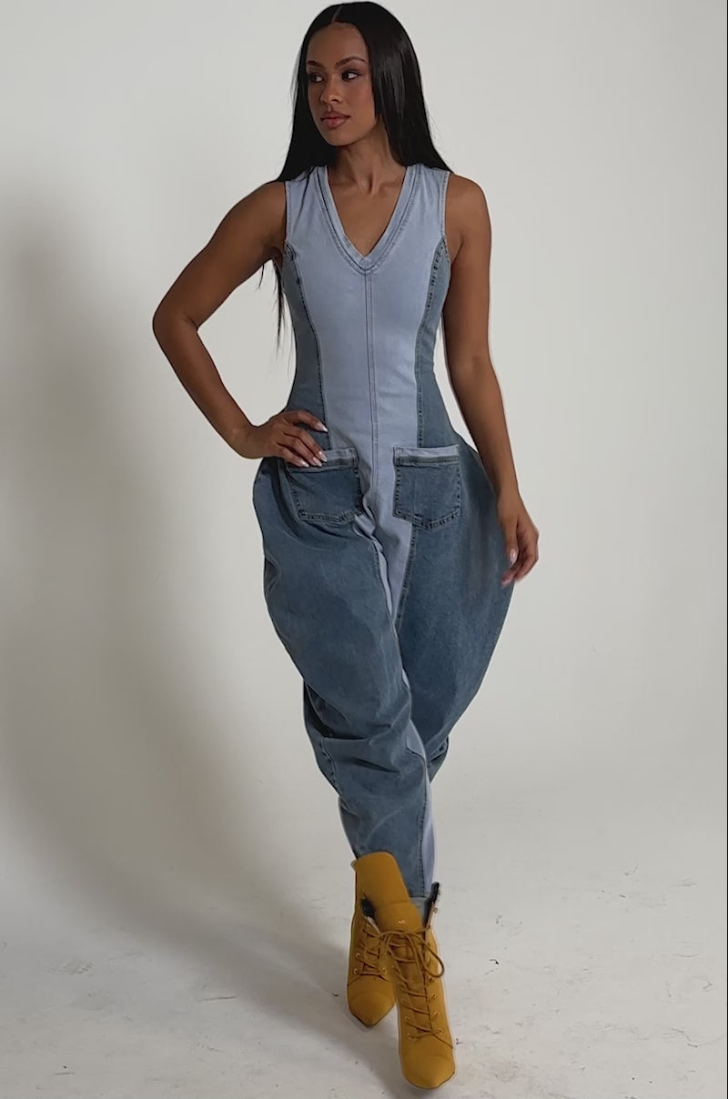 A video of a woman in the TALK OF THE STREET DENIM JUMPSUIT styled with tan high-heeled boots against a plain, neutral background.