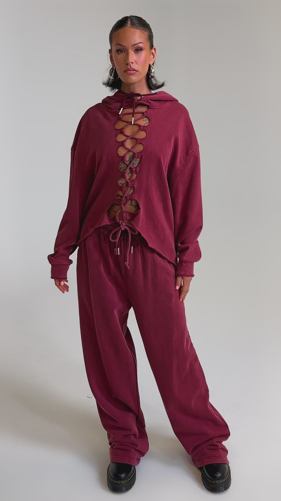 A video of a woman in the LACED UP FOR GOOD JOGGER IN PLUM, paired with matching wide-leg pants and black chunky shoes, posing against a plain light background.