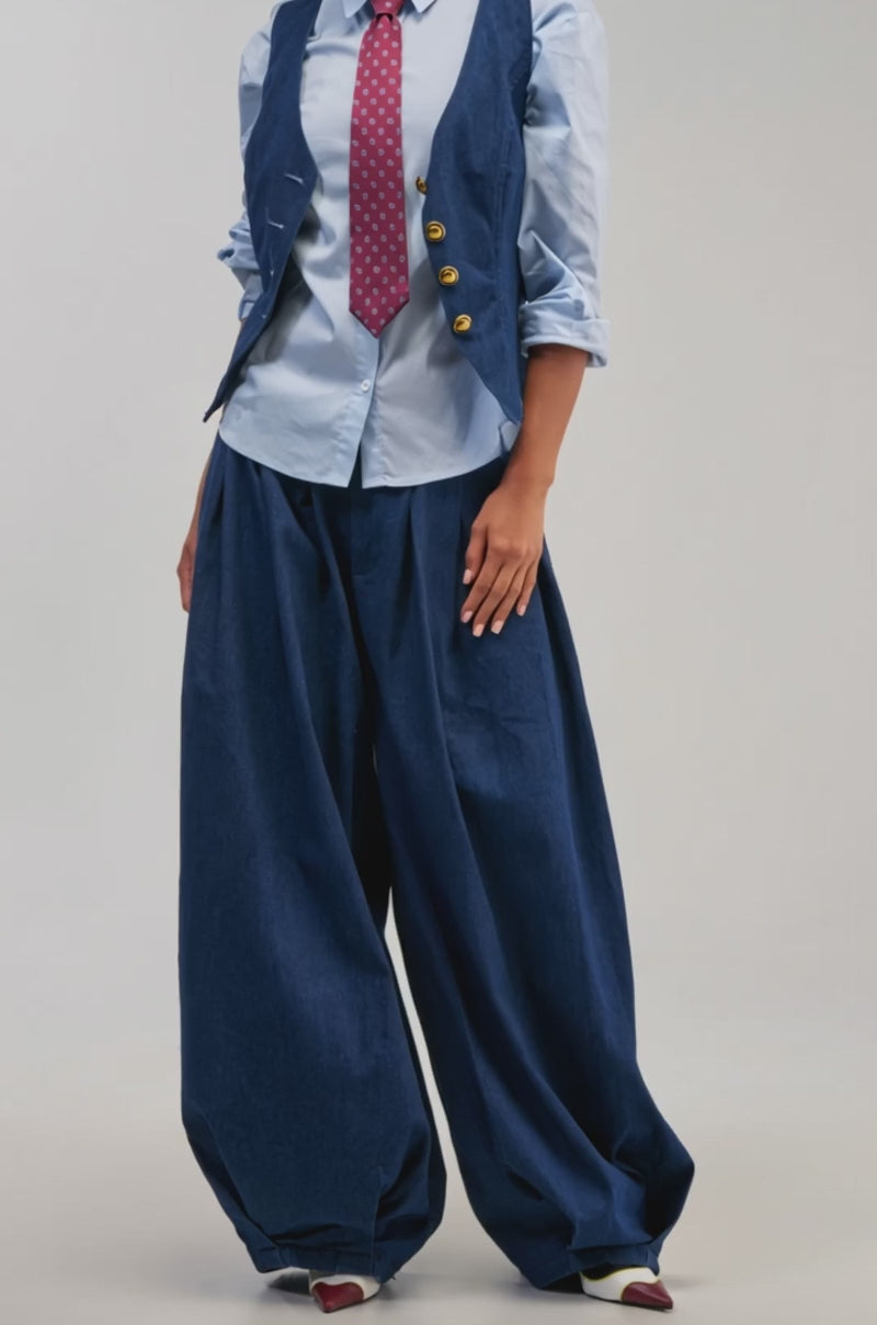 Video of a woman modeling the BUSINESS IN THE FRONT TROUSER—a chic, wide-leg blue tailored pant—a stylish individual stands on stone steps.