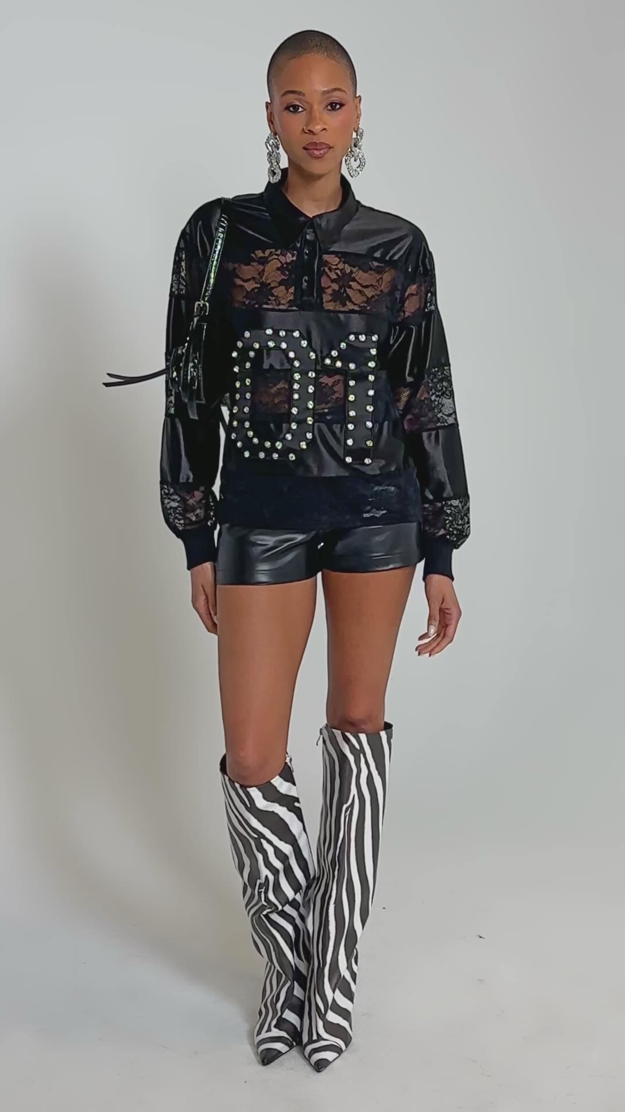 Video of woman modeling the AT THE GAME PU LACE JERSEY TOP with a rhinestone "01" graphic and sheer floral lace paneling.