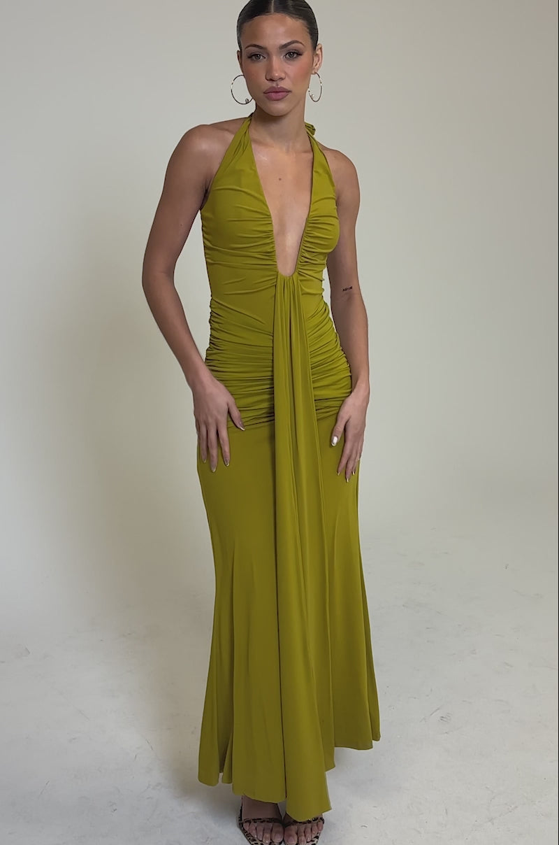 Video of woman modeling the ISLAND LOVE MAXI DRESS IN GREEN. She accessorizes with heeled sandals, and wears her long hair styled in a braid.