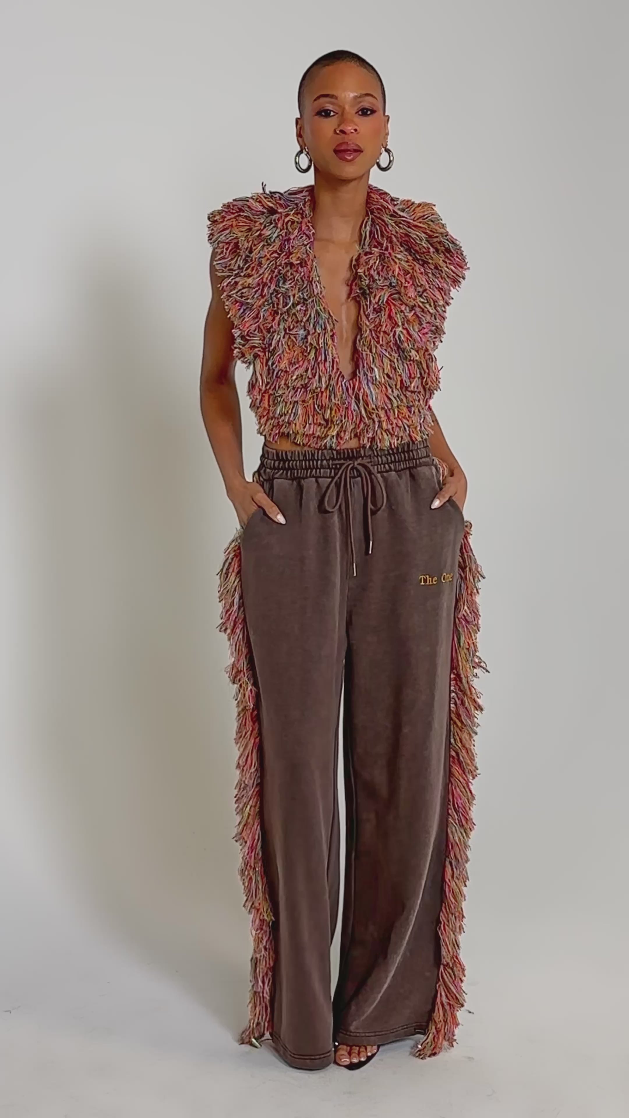 Video of woman modeling the THE ONE FRINGE BLOUSE—a sleeveless, multicolored shaggy-textured top that makes a bold statement against a plain background.