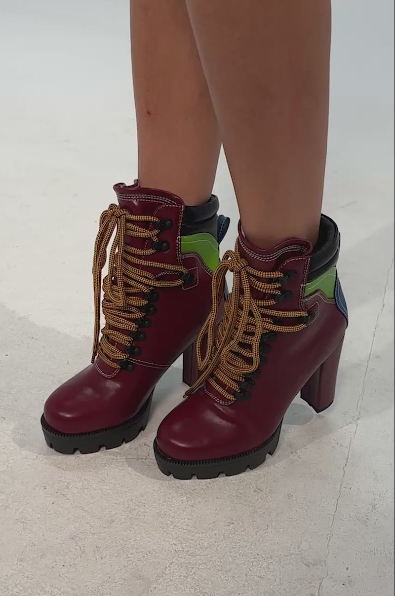 Video of woman modeling the AZALEA WANG DEUTCH MULTI SPORTY BLOCK BOOTIE—red, green, and blue high-heeled lace-up boots with thick tan laces and chunky black soles against a plain background.