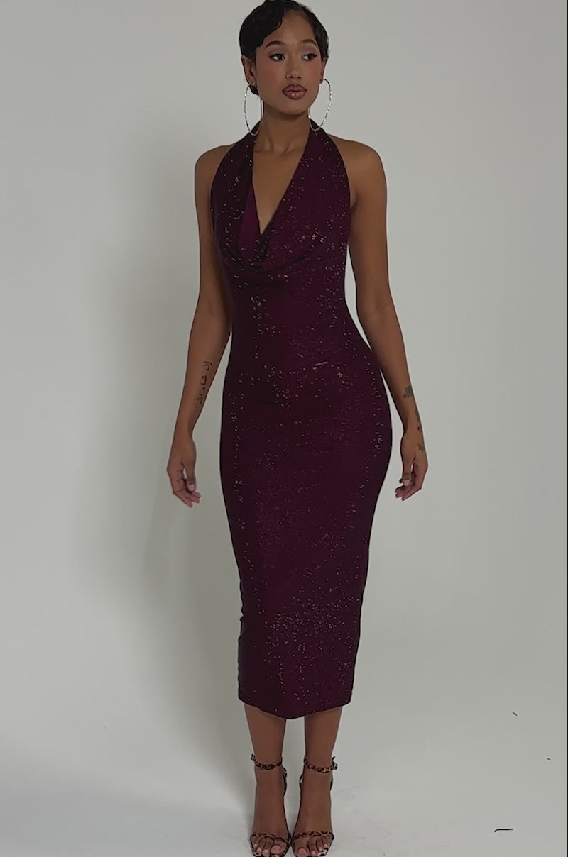 Video of woman modeling the POPPIN' BOTTLES RHINESTONE MAXI DRESS IN PURPLE, a sleeveless, form-fitting party dress with shimmering magenta rhinestones. She pairs it with large hoop earrings and strappy heels against a neutral background