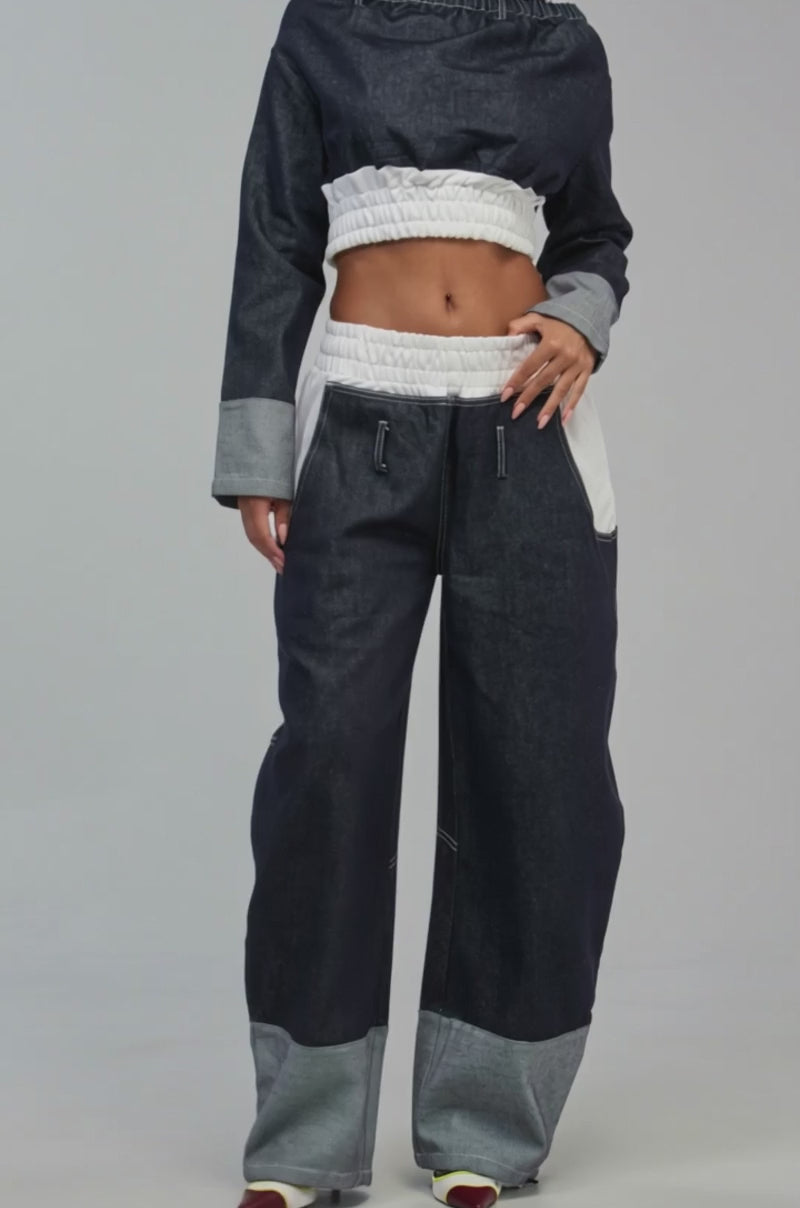 Video of a woman modeling the WHO SHE OFF THE SHOULDER DENIM SWEATSHIRT paired with matching denim pants featuring white accents.