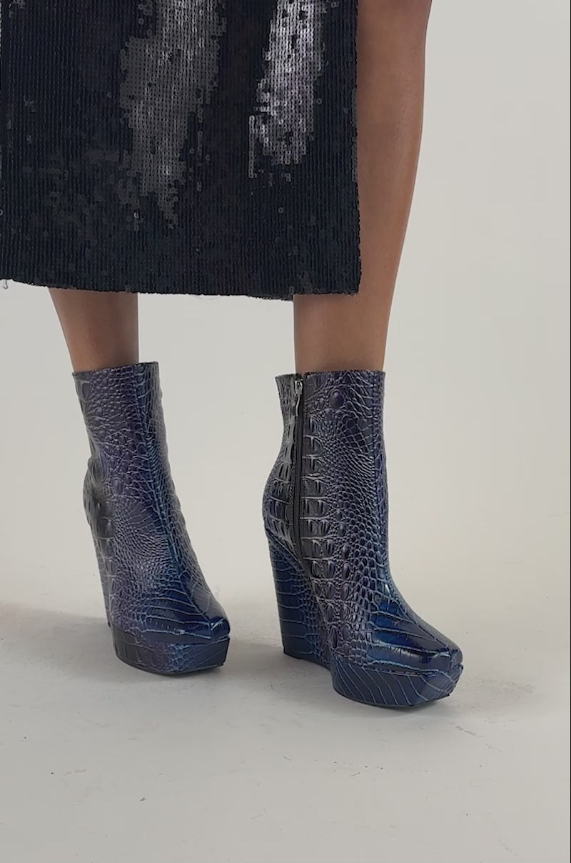 Video of a woman modeling the AZALEA WANG ALESSANDRA MULTI CROC WEDGE BOOTIE, featuring crocodile-embossed texture, blue wedge heels, and zippered sides.