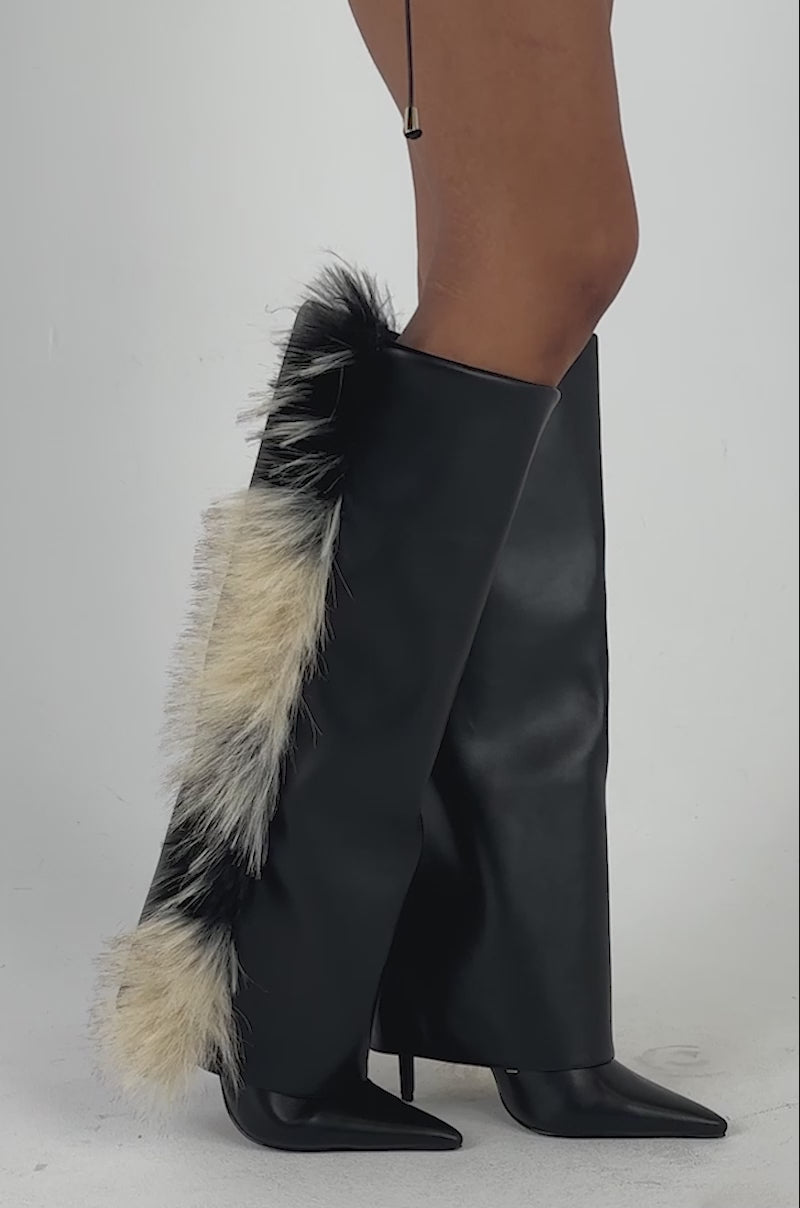 Video of a woman modeling the AKIRA GOLD KAIRA BLACK MULTI FUR TRIM DETAIL BOOT—striking black stiletto boots featuring tan and black faux fur trim on one side.