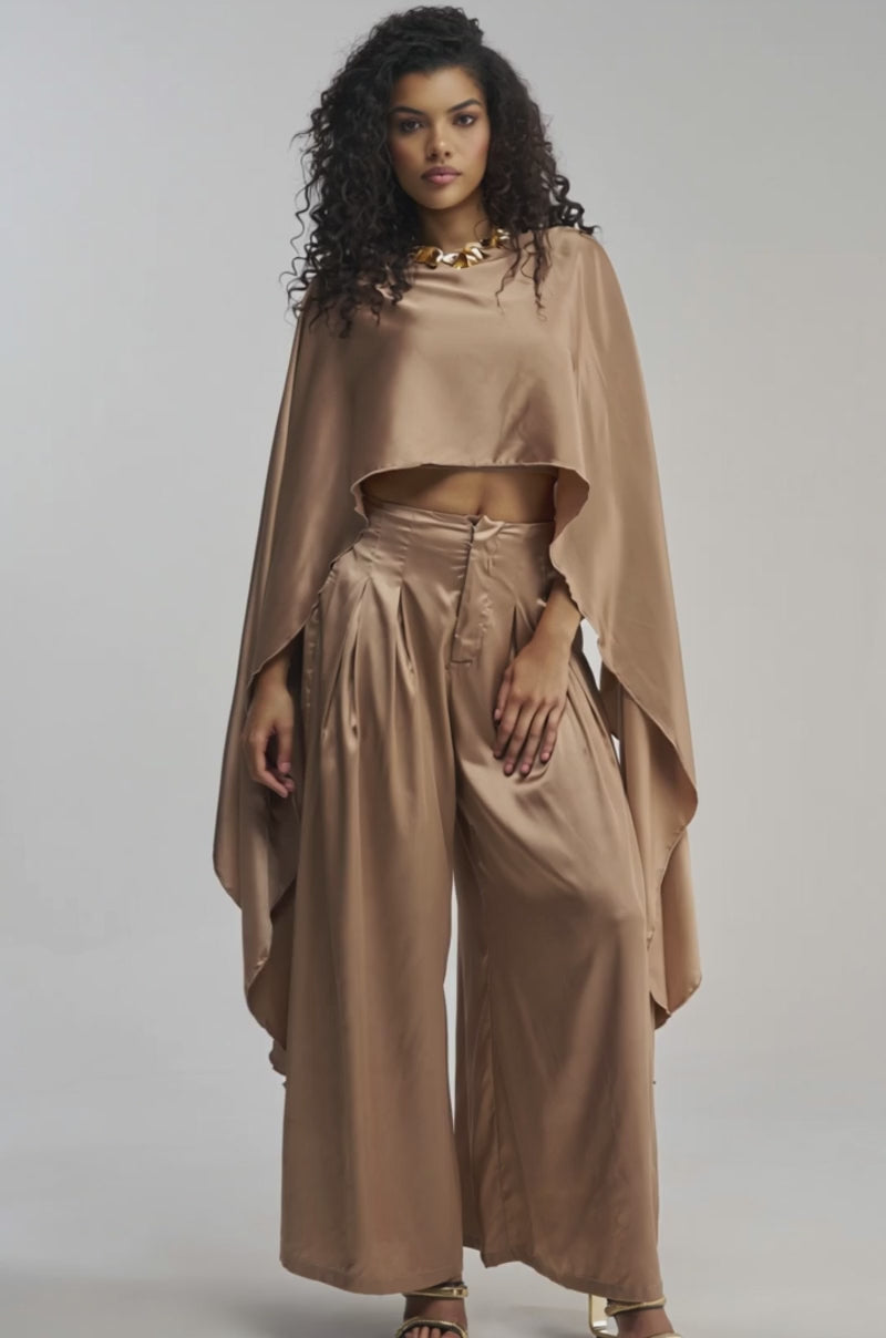Video of woman modeling the GOLDEN HOUR BLOUSE, a gold satin top with long, flowing panels and a distinctive draped silhouette