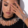 A woman with long dark hair and flawless makeup covers one eye with her hand, which is adorned with the PRINCESS DI BLING HAND BRACELET. She wears large, dangling earrings and a matching necklace paired perfectly with her black top.