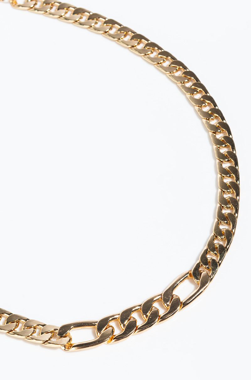Close-up image of the REBEL GIRL CHAIN CHOKER arranged in a partial loop on a white background. The gold chain links are large, shiny, and interlocking, creating a luxurious and elegant appearance.