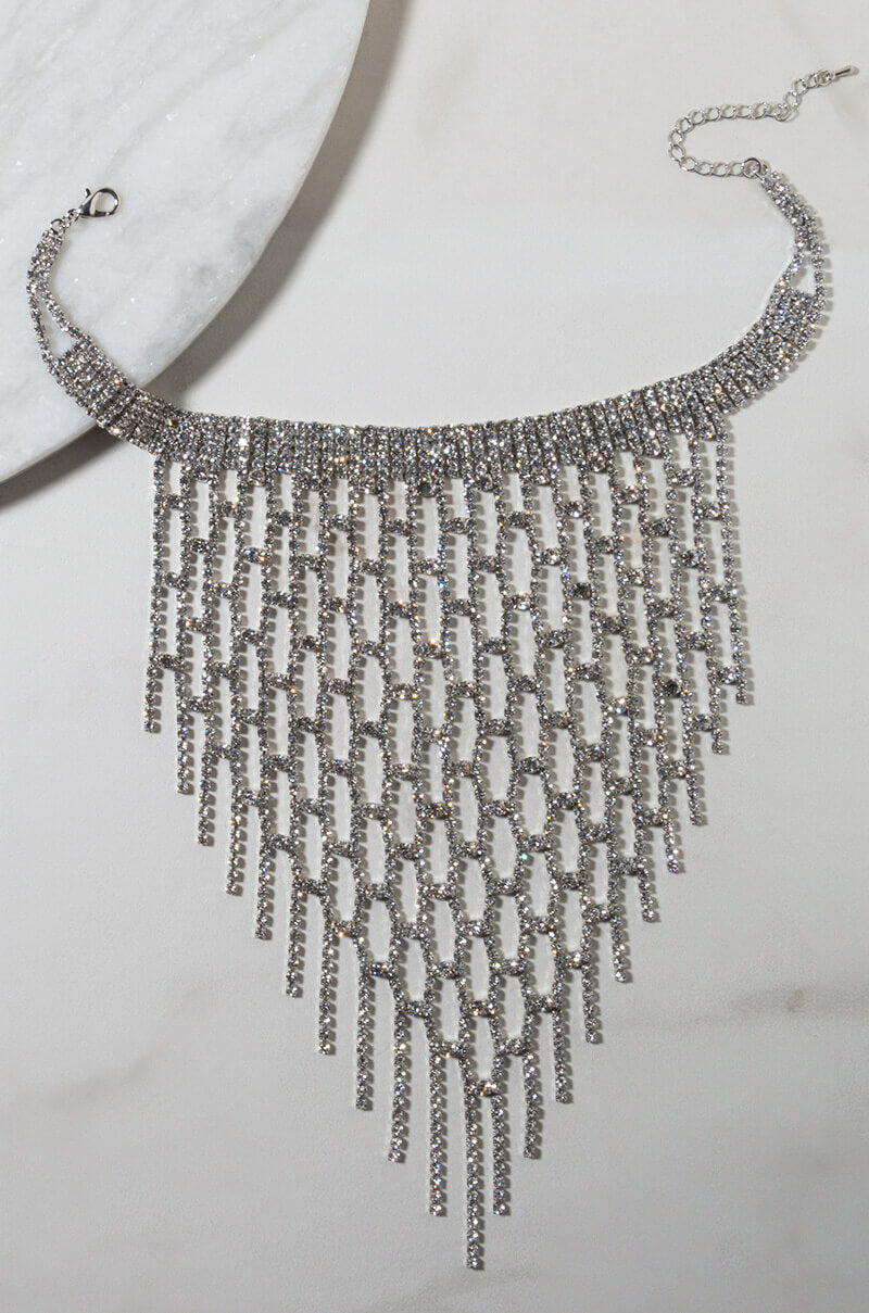Displayed on a light surface is the sparkling SAY YOU LOVE SOMEONE NECKLACE GOLD by H&D Accessories. This shimmering necklace features multiple dangling strands that create a dramatic, triangular fringe design, with the closure chain visible at the top.