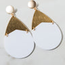 The Sexy Dangle Earrings showcase circular studs adorned with triangular gold-tone accents, which suspend large, white teardrop-shaped pendants. These earrings boast a modern, minimalist design that seamlessly combines metallic gold with matte white elements.