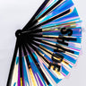 The SHADE FAN showcases an iridescent design with black folding ribs and the word "SHADE" prominently printed in bold black letters on its reflective surface. Partially opened, the fan displays a glossy, holographic appearance against a white background.