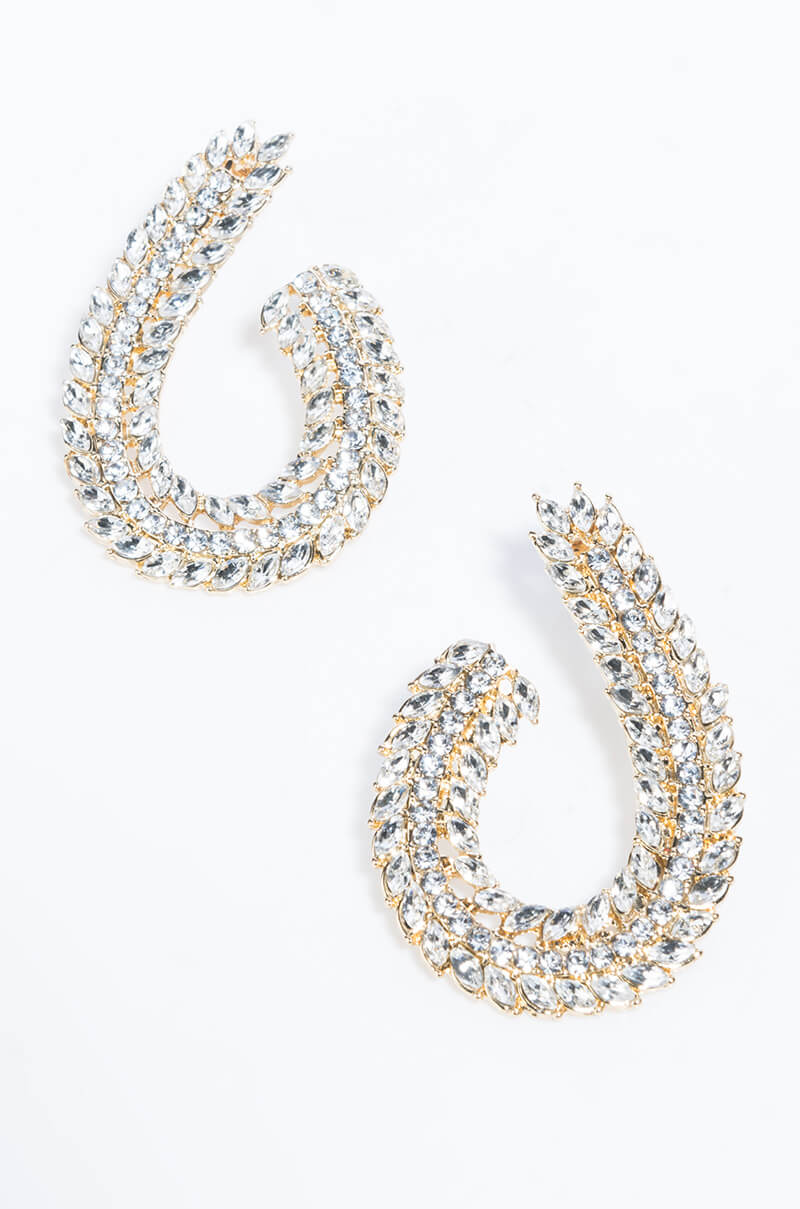 Close-up of the SIDE SLING RHINESTONE EARRING, a pair of elegant, gold-tone earrings designed in a teardrop shape. Each earring is adorned with multiple rows of sparkling, clear rhinestones, creating a luxurious and dazzling appearance. The earrings are placed on a plain white background.