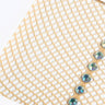 Close-up of the SINGLE RHINESTONE LINE TIGHT, showcasing a diamond-patterned mesh fabric in light beige. A row of small, round, iridescent rhinestones, reflecting shades of blue and green, is neatly lined up along one edge.