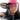 A person wearing a bright pink hat and YAPPER TREND SUNNIES rides a motorcycle. The motorcycle's rearview mirror and headlight are visible. The person has long, dark hair and a serious expression. The image is taken from a low-angle, close-up perspective.