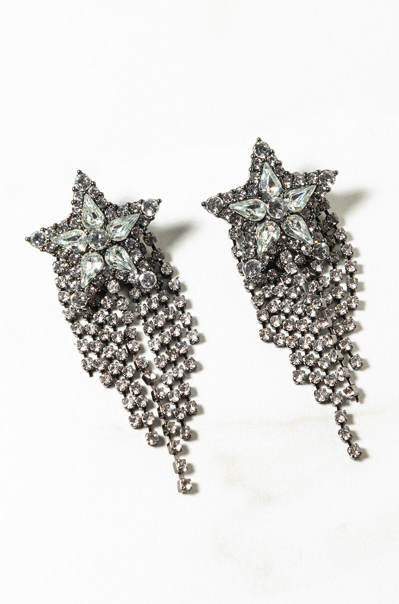 Introducing the STARBURST RHINESTONE FRINGE EARRING: a pair of stunning earrings featuring star-shaped studs encrusted with clear gemstones, cascading into multiple dangling strands of small, sparkling beads. With a silver metallic finish and intricate design, these earrings shine brilliantly.