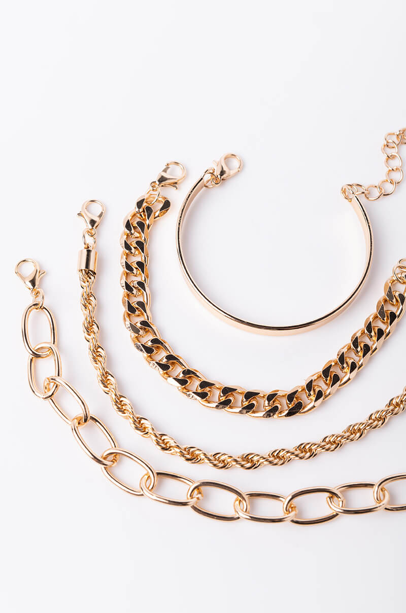 A photo showcases the "SUMMER READY CHAIN BRACELET SET," featuring four distinct gold bracelets with unique designs. The set includes a sleek bangle, a thick chain link bracelet, a twisted rope chain bracelet, and a large oval link chain bracelet, all elegantly displayed against a plain white background.