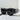 TELL ME NOTHING RHINESTONE SUNGLASSES ASSORTED feature an array of small, shimmering rhinestones along the top rim and temples of their black oversized frame. The dark-tinted lenses enhance the bold, glamorous style. These stunning sunglasses are showcased on a light-colored surface with a minimalist background.