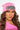 A person with long, wavy brown hair is wearing THE AFTER PARTY GEM KNIT HAT, a bright pink beanie adorned with a large, jeweled brooch. They have soft makeup featuring bold eyeliner and nude lipstick, while the background is plain white.