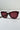 A pair of stylish TIERRA OVERSIZED SUNGLASSES with maroon frames and matching tinted lenses is placed on a white surface with a light grey background.