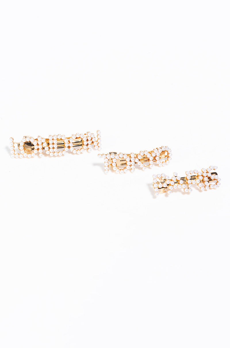 A set of three TOKYO LONDON PARIS PEARL hair clips against a white background. Each hair clip is adorned with small gemstones, featuring the words "GLAM," "BOSS," and "QUEEN" respectively, spelled out in golden letters embellished with the stones.