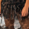 Close-up of a person wearing the SEXY CAMO OTT MESH MAXI SKIRT. The focus is on the midsection, showing the intricate detailing of the sheer camouflage-patterned fabric with layered ruffles and the person's hands gently resting at their sides.